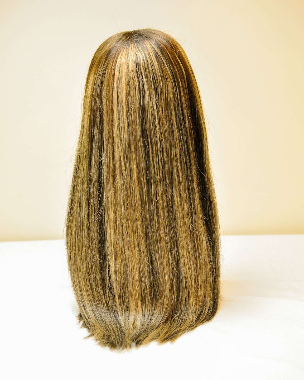 Long straight brown hair extension with blonde highlights stands upright.