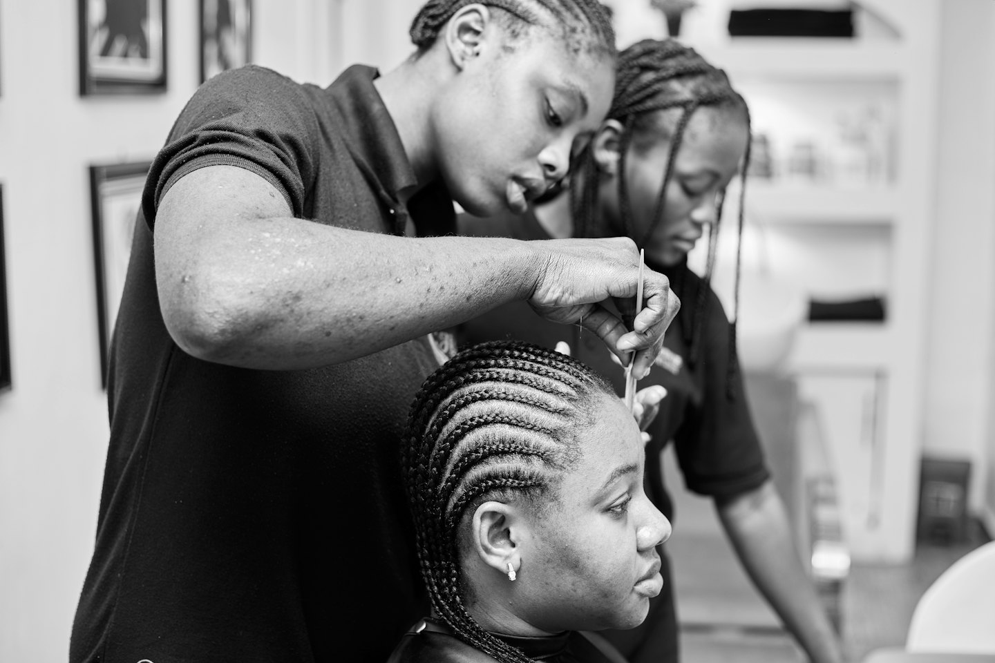 Stylist braids cornrows on client in salon.